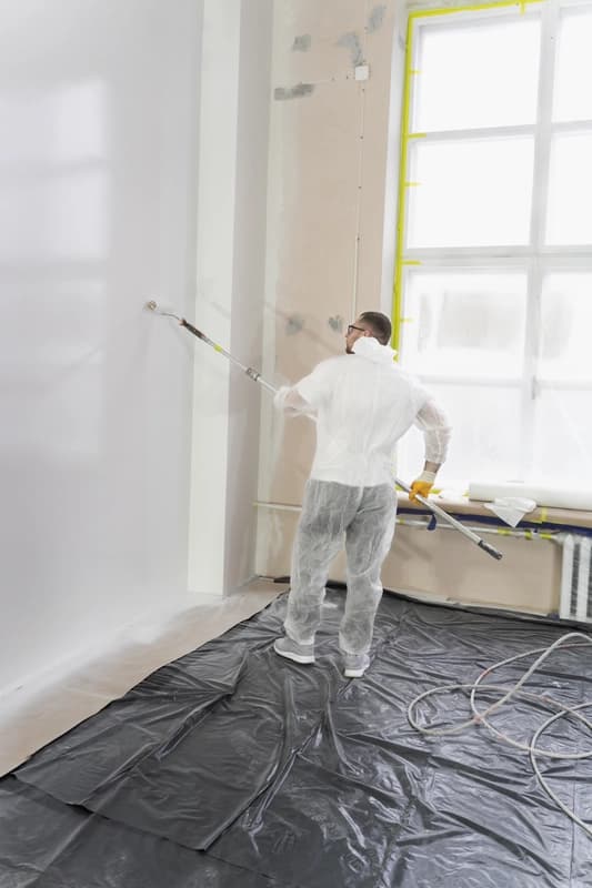 Peintre professionnel en train de peindre un mur intérieur