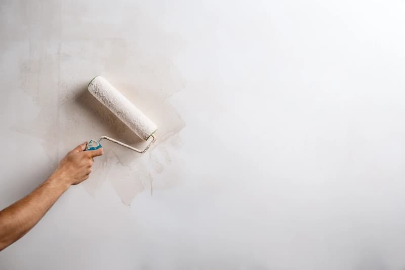 Gros plan d'un mur en cours de peinture au rouleau, travaux de peinture intérieure