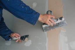 Plâtrier préparant un mur avant peinture, remise en état après sinistre